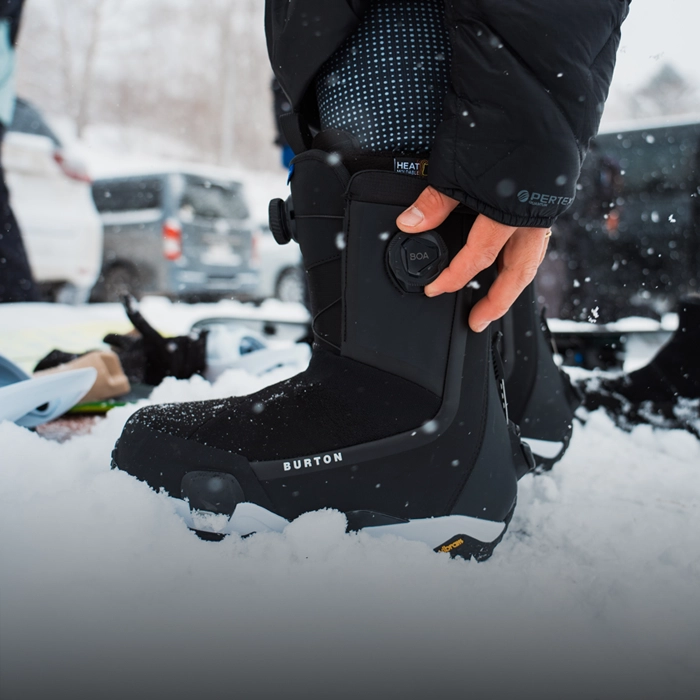 A snowboarder connecting their boots to their board with secure bindings.